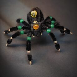 Handmade black spider decoration made with pipe cleaners, featuring crystal bead embellishments in green, amber, and yellow. Perfect for Halloween decor or a unique desk ornament.